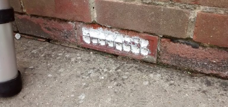Air brick installed at the bottom of a brick wall